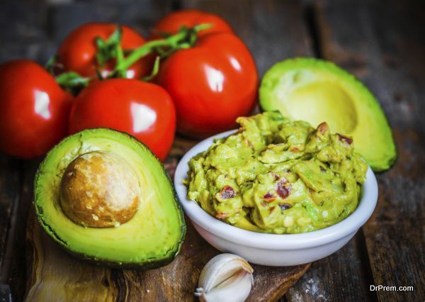 Guacamaole with bread and avocado on rustic wooden background