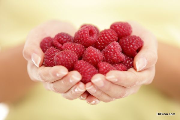 Raspberries. Woman showing raspberries in closeup. Healthy food and raspberry concept.