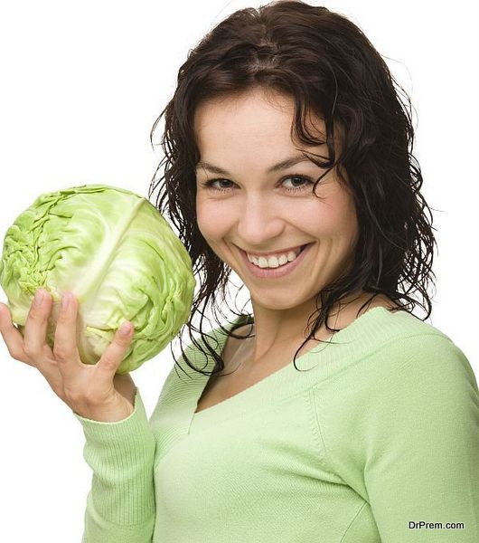 Beautiful young girl with green cabbage, isolated over white