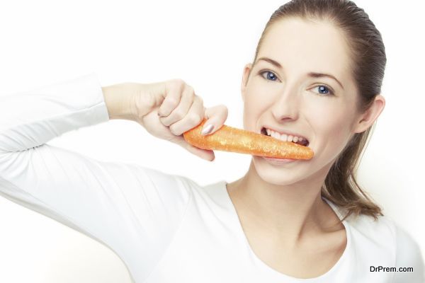 young woman eating the carrot, over white background