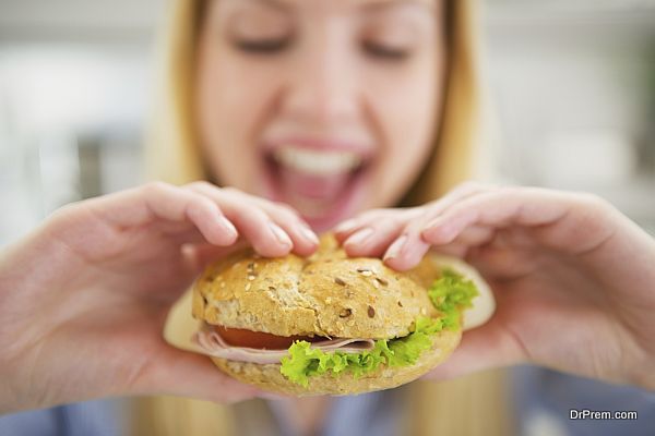 Closeup on happy young woman eating burger