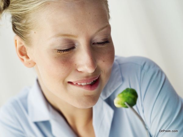 Young woman looking at a Brussels sprout on a fork
