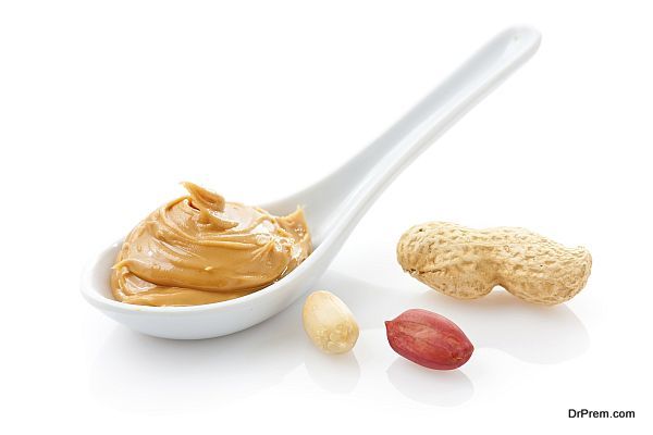Creamy peanut butter in a white spoon with peanuts
