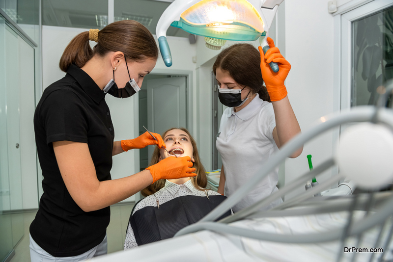 Female dentist and young assistant doing repairing patient tooth in dental ambulant