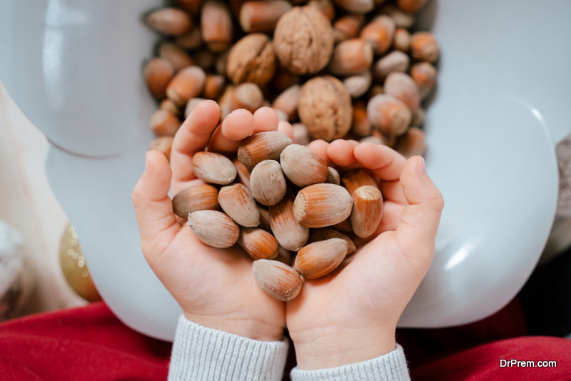 Horizontal view of unrecognizable little kid hands full with december season hazelnuts. Christmas and seasonal food and ornaments background concept.
